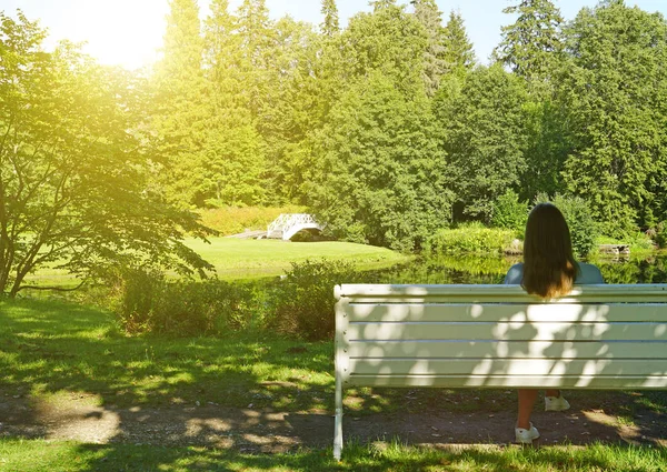 Mulher sentada no banco no parque no verão . — Fotografia de Stock