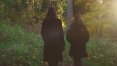Kadın ve kızı sonbahar ormanında yürür..