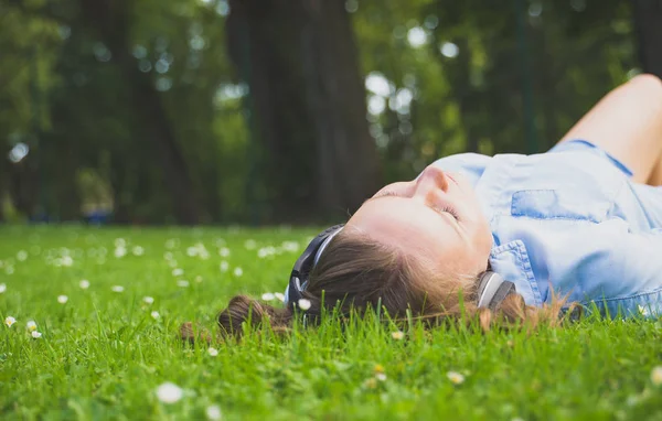 Kvinnan i trådlösa hörlurar kopplar av i parken. — Stockfoto