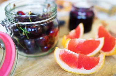 Kavanozda greyfurt dilimleri ve kirazlar.