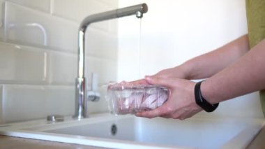 Mağazadan sonra kadın ürünleri musluğun altında dezenfekte ediyor. Covid-19 önleme.