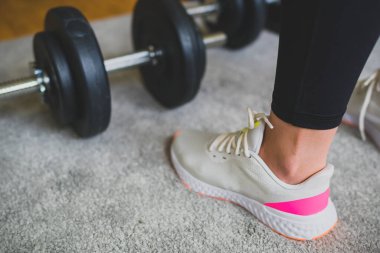 Kadın dambıllarla antrenman yapmaya hazırlanıyor. Evde fitness eğitimi kavramı.