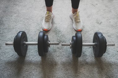 Kadın dambıllarla antrenman yapmaya hazırlanıyor. Evde fitness eğitimi kavramı.