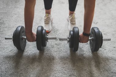 Kadın dambıllarla antrenman yapmaya hazırlanıyor. Evde fitness eğitimi kavramı.