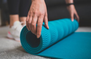 Yoga minderi yuvarlayan kadın. Evde fitness eğitimi kavramı.