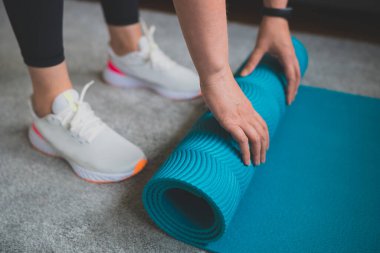 Yoga minderi yuvarlayan kadın. Evde fitness eğitimi kavramı.