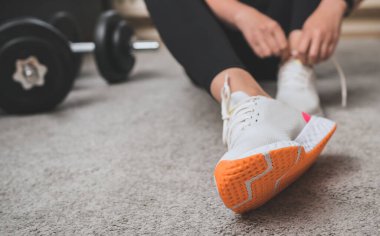 Egzersizden önce ayakkabı bağı bağlayan bir kadın. Evde fitness eğitimi kavramı.