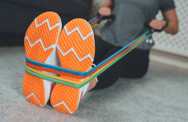 Woman doing exercises with resistance bands at home.
