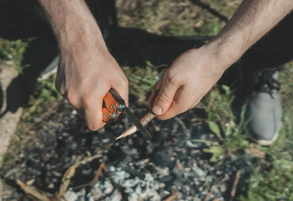 Człowiek Nożem Tnący Drewniany Kij Nad Ogniskiem — Zdjęcie stockowe