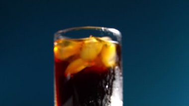 Mavi arka planda buz küpleri olan bir bardak kola. Metin için yer.