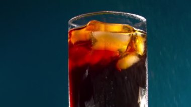 Mavi arka planda buz küpleri olan bir bardak kola. Metin için yer.