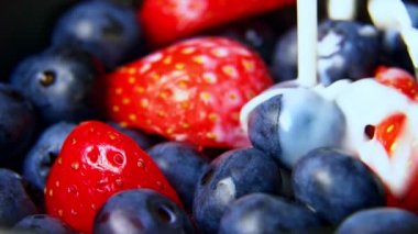 Yabanmersinleri ve çileklerin üzerine süt dökülüyor. Makro çekim.