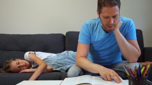 Pappa gör läxor med dottern. Han läser en bok, men hans dotter är inte intresserad.. — Stockvideo