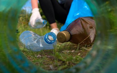 Gönüllü ormanda şişe topluyor. Şişenin boynundan bak..