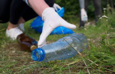 Gönüllüler ormanda şişe topluyor. Çevre kirliliği kavramı.