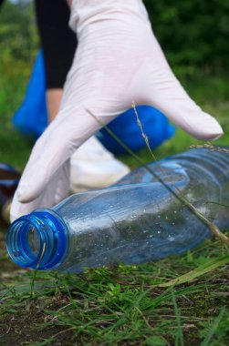 Gönüllü ormanda şişe topluyor. Çevre kirliliği kavramı.