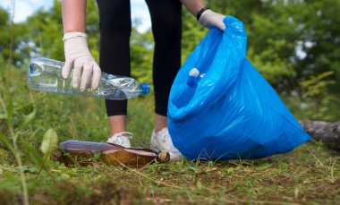 Gönüllü ormanda şişe topluyor. Çevre kirliliği kavramı.