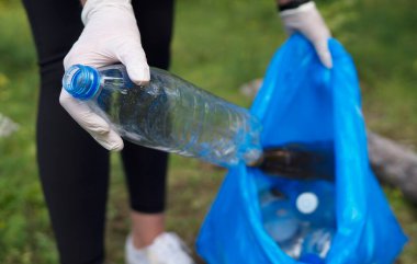 Gönüllü ormanda şişe topluyor. Çevre kirliliği kavramı.