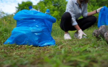 Gönüllü ormanda şişe topluyor. Çevre kirliliği kavramı.