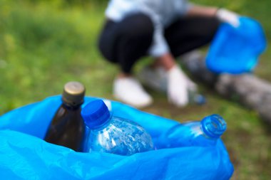 Gönüllü ormanda şişe topluyor. Çevre kirliliği kavramı.