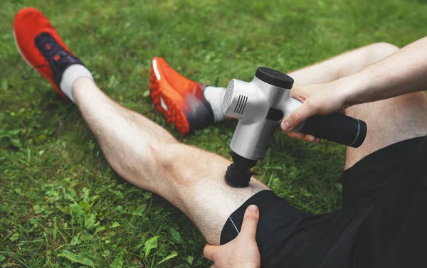 トレーニング後のマッサージ パーカッション デバイスで脚をマッサージする男 — ストック写真