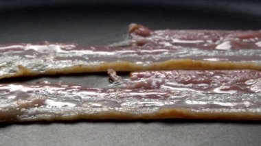 Kızartma tavasındaki pastırma dilimlerinin yakın plan görüntüsü.