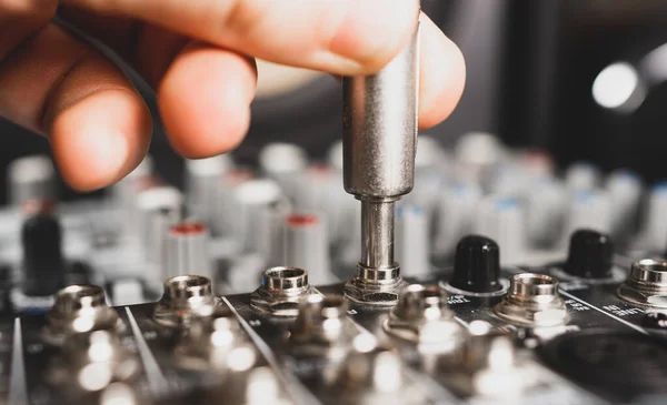 Sound engineer plugging jack audio cable on studio mixer.