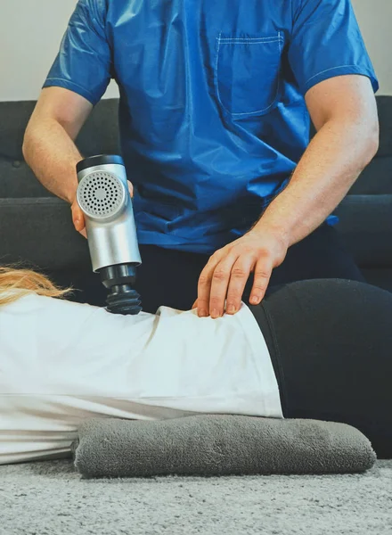 Terapeuta Masajeando Espalda Mujer Casa Con Dispositivo Percusión Masaje — Foto de Stock