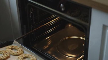 Kadın fırına fıstık ve halka kurabiyeleri koyuyor..