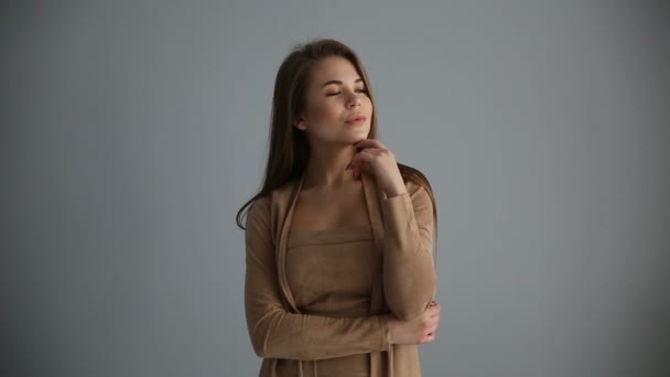 Hermosa chica feliz posando positivamente contra una pared gris — Vídeos de Stock