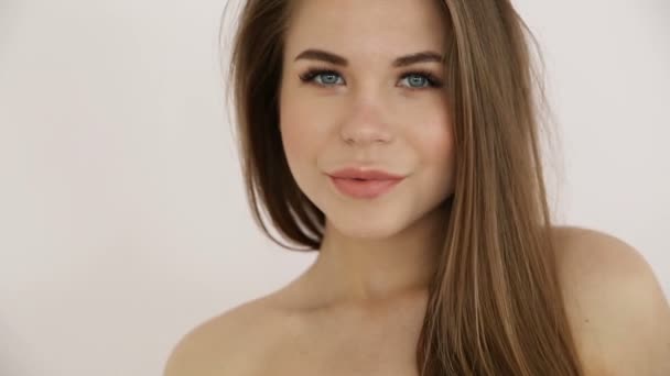 Hermosa chica rubia con hombros desnudos posando contra una pared blanca de cerca — Vídeos de Stock