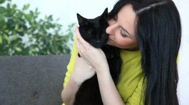 aşk için pets. siyah bir kedi ile güzel esmer kız evde oturma odasında kanepede rahatlatıcı.