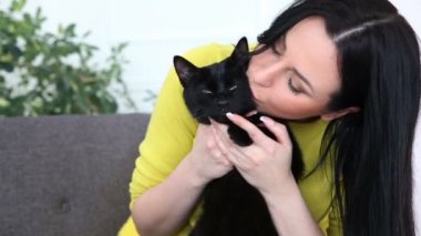 aşk için pets. siyah bir kedi ile güzel esmer kız evde oturma odasında kanepede rahatlatıcı.