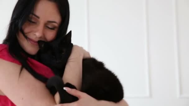 Liefde voor huisdieren. mooi donker-haired meisje dansen met een zwarte kat thuis in de woonkamer — Stockvideo