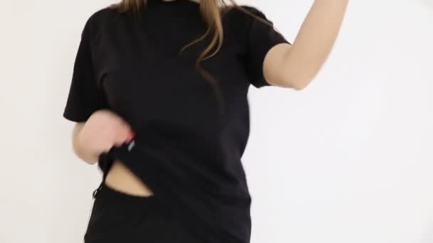 A teenage girl in black hip-hop clothes and a cap dances at the white wall- close-up, handheld shoot, small depth of field — Stock Video