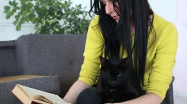 aşk için pets. siyah bir kedi ile güzel esmer kız evde oturma odasında kanepede rahatlatıcı.