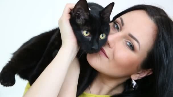 Amor por las mascotas. hermosa chica de pelo oscuro con un gato negro es relajarse en casa en la sala de estar en el sofá . — Vídeo de stock