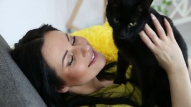 aşk için pets. siyah bir kedi ile güzel esmer kız evde oturma odasında kanepede rahatlatıcı.
