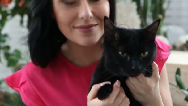 Amor por animais de estimação. bela menina de cabelos escuros com um gato preto é relaxante em casa no quarto de cama — Vídeo de Stock