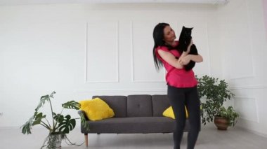 aşk için pets. siyah bir kedi evde oturma odasında dans güzel esmer kız