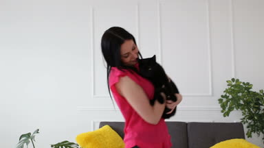 aşk için pets. siyah bir kedi evde oturma odasında dans güzel esmer kız