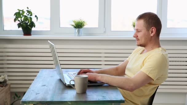 Чоловік фрілансер працює дистанційно вдома на ноутбуці — стокове відео