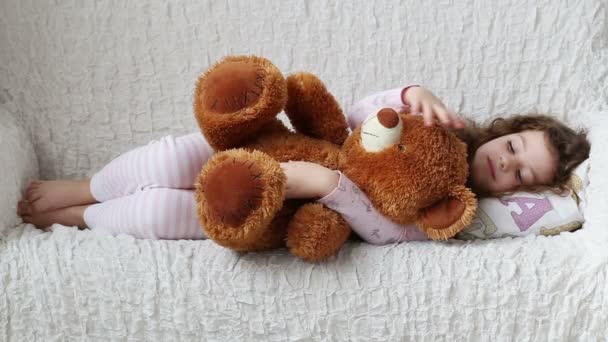 一个小女孩和一只泰迪熊在沙发上休息 — 图库视频影像
