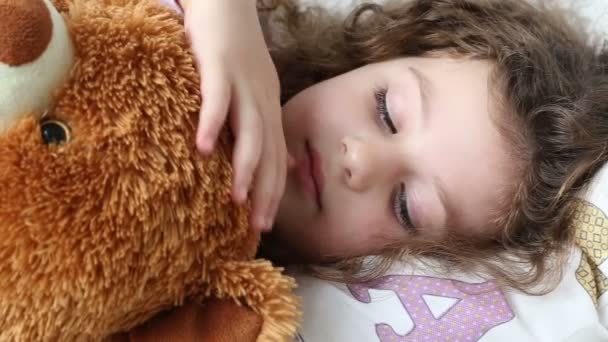 Una niña descansando en el sofá con un oso de peluche, primer plano, seguimiento de disparo — Vídeos de Stock