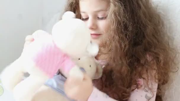 Κοριτσάκι παίζει με teddy φέρει στον καναπέ - παρακολούθηση βολή — Αρχείο Βίντεο