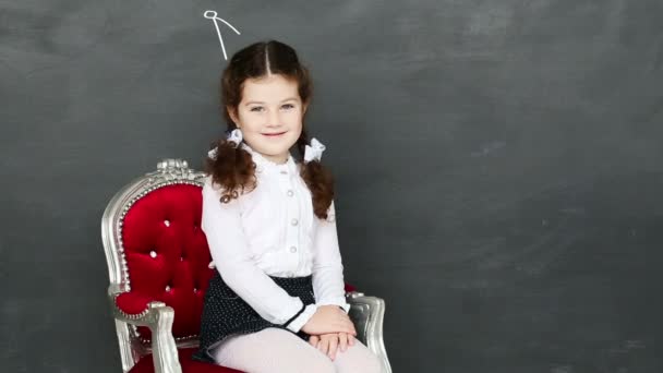 Niña sentada en una silla cerca de una junta escolar — Vídeo de stock