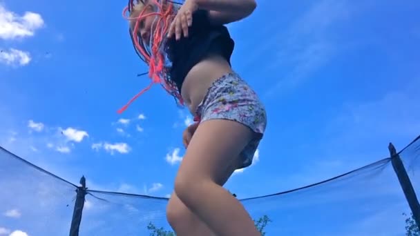 Infancia sin preocupaciones, feliz verano. hermosa chica con coletas africanas saltando en un trampolín - cámara lenta — Vídeo de stock