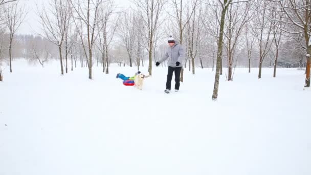 快乐的家庭与孩子和狗在雪覆盖的公园在冬天乐趣 — 图库视频影像