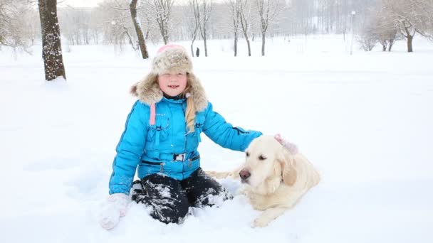 Miłość dla zwierząt - dziewczyna odpoczywa z golden retriever w śniegu w parku — Wideo stockowe