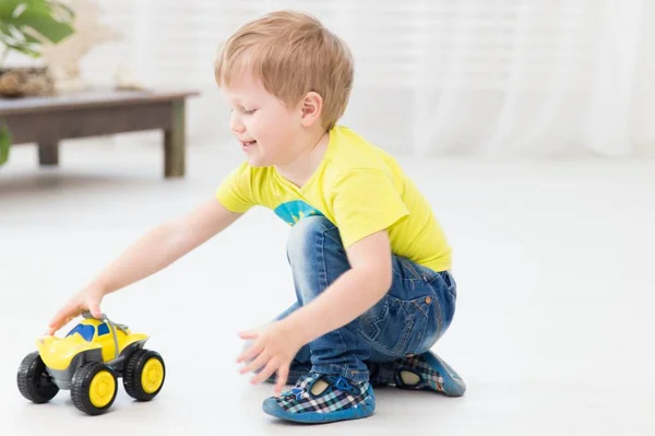 幸せな子供時代の家でおもちゃの車で遊んで少し陽気な少年 — ストック写真